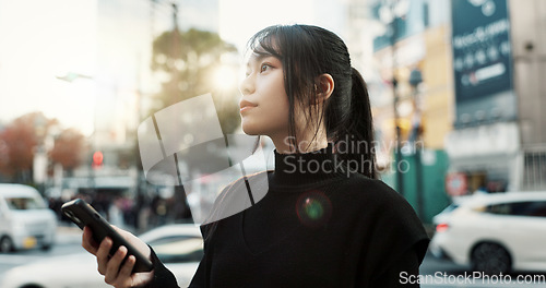 Image of Walking, cellphone and Japanese woman in the city networking on social media or the internet. Phone, adventure and young female person commuting for travel in road of urban town in Kyoto Japan.