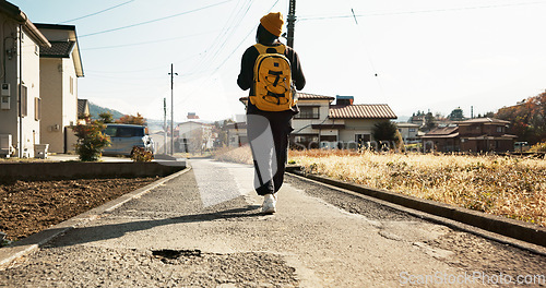 Image of Woman, walk in street and travel with backpack in neighborhood, adventure on holiday or commute. Back view, journey and traveller on road with bag in residential area for vacation or weekend trip