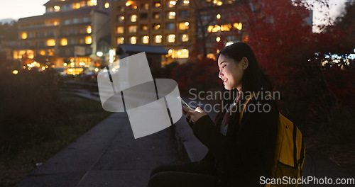 Image of Asian woman, phone and night at city for social media, communication or outdoor networking. Female person relax on mobile smartphone in the late evening for online chatting in urban town of Japan