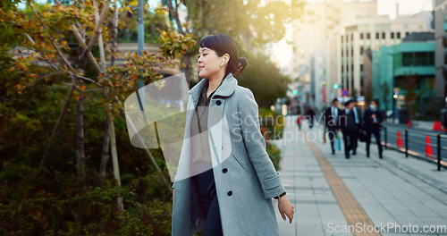 Image of Woman, Asian and walking, travel or commute to work with professional in city with earphones. Listening to music on journey, podcast and commuter on urban street or sidewalk in Tokyo with playlist