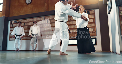 Image of Aikido, sensei and Japanese students with discipline, fitness and action in class for defence or technique. Martial arts, people or fighting with training, uniform or confidence for culture and skill