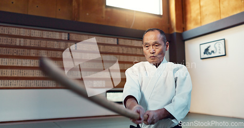 Image of Aikido sword, martial arts and mature man strike for training, self defense or combat technique. Dojo, Japanese person and expert with wooden weapon for skills development, attack or bokken practice