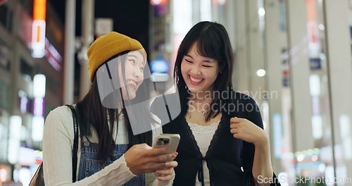 Image of Woman, friends and Japanese or cellphone in city street for night communication, research or location. Female person, Tokyo road and lights internet network for social media news, adventure or travel