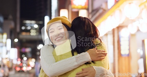 Image of Woman, friends and hug in Japanese city or happy reunion for party night, adventure or Tokyo. Female people, embrace and dark or bokeh on street with light or international travel, journey or evening