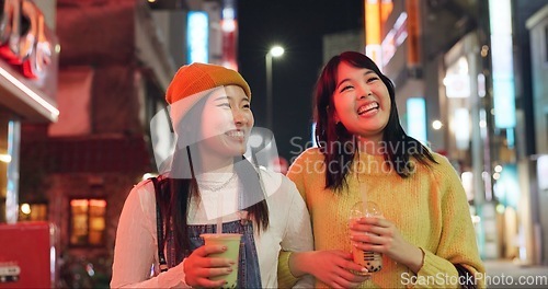 Image of Night, travel and Japanese women in a city walking, talking and bonding with milkshake drink outdoor. Happy, female and friends in Japan with bubble tea boba, conversation and fun evening adventure