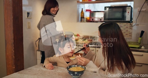 Image of Family, Japanese and mother feeding daughter in kitchen of home for growth, health or nutrition. Food, girl eating ramen noodles in apartment with parent and grandparent for diet or child development