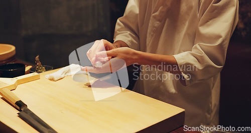 Image of Hands, food and sushi chef in restaurant for traditional Japanese cuisine or dish closeup. Kitchen, cooking or seafood preparation and person working with fresh gourmet meal recipe ingredients