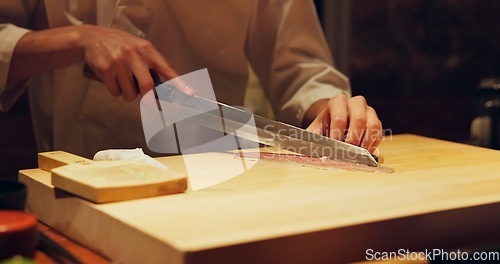 Image of Hands, food and chef cutting sushi in restaurant for traditional Japanese cuisine or dish closeup. Kitchen, cooking seafood for preparation and person working with gourmet meal recipe ingredients