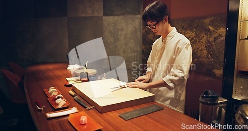 Image of Japan chef, restaurant and knife for sushi and precision with sharp blade for gourmet fish menu in hotel. Asian man, hands and culinary artist on job by wood board, table and raw seafood on plate