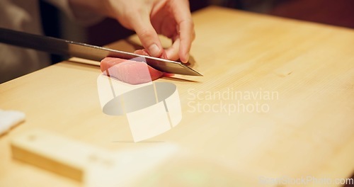 Image of Hands, food and sushi chef cutting fish in restaurant for traditional Japanese cuisine or dish closeup. Kitchen, cooking on table for seafood preparation and person working with gourmet ingredients