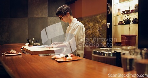 Image of Chef, cooking and sushi in kitchen of restaurant for traditional food, cuisine or gourmet dish. Luxury, catering and salmon with Japanese man cook cutting fish for seafood meal ingredients or recipe