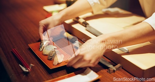 Image of Hands, cooking and chef serving sushi in restaurant for traditional Japanese cuisine or dish closeup. Kitchen, service or preparation of seafood and person working with gourmet recipe ingredients