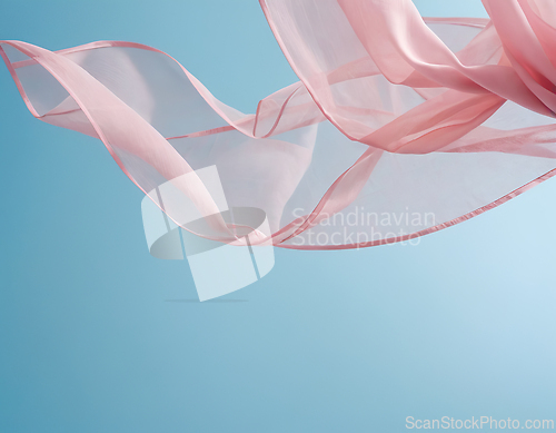Image of Flying pink fabric wave on blue background and illuminated by su