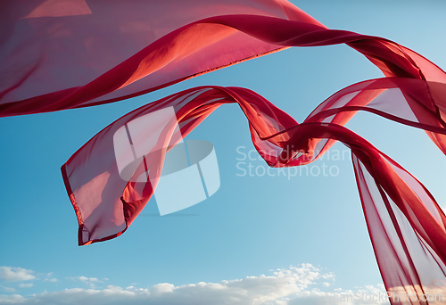 Image of Flying transparent red fabric wave on blue sky background and il