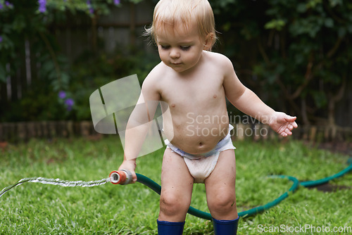 Image of Baby, playing with hose and garden, water and development with growth, curiosity and backyard. Toddler, child and infant in gardening, alone and childhood for skills, milestone and coordination