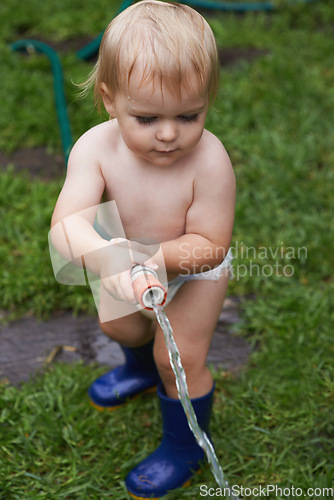 Image of Child, gardening and water grass with hose and learning to care for backyard and lawn. Kid, outdoor and play with hosepipe in summer, nature or environment and helping with sustainable growth at home