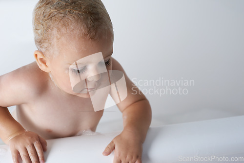 Image of Kid, baby and boy in bathtub of water for morning routine, skincare and wellness at home in bathroom. Toddler, wet child and washing with soap, foam and bubbles for cleaning, hygiene or mockup space