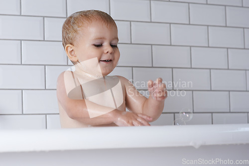 Image of Baby, child and playing with bubbles in bath of water for morning routine, skincare and wellness at home. Happy boy, kid and cleaning in tub with soap, foam and washing for fun, hygiene and bathroom