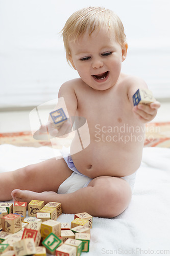 Image of Playing, kid and baby with his learning cubes, happiness and smile with joy, fun and education. Growth, cheerful and child development with toys, active and excited with games, wooden blocks or peace