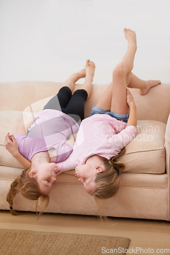 Image of Tongue out, sisters or upside down on couch for love, bond or care to relax in a fun family home. Friends, children or girl siblings on sofa in lounge together to play games with freedom or kids
