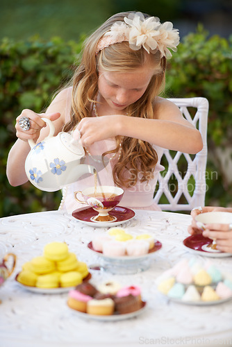 Image of Girl, child and pouring tea in garden with party for birthday, celebration and playing outdoor in home. Person, kid and porcelain cup in backyard of house with dress up, beverage and role play fun