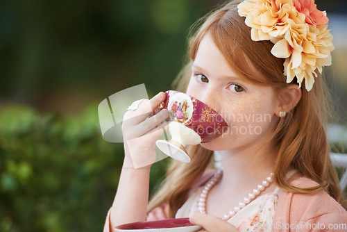 Image of Girl, child and portrait of drinking tea in garden with party for birthday, celebration and playing outdoor. Person, kid and porcelain cup in backyard with dress up, beverage and role play with fun