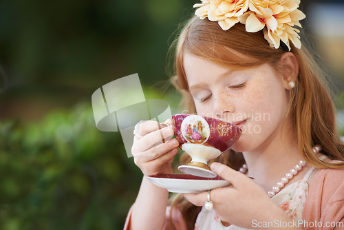 Image of Girl, child and drinking tea in garden with party for birthday, celebration and playing outdoor in home. Person, kid and porcelain cup in backyard of house with dress up, beverage and role play fun