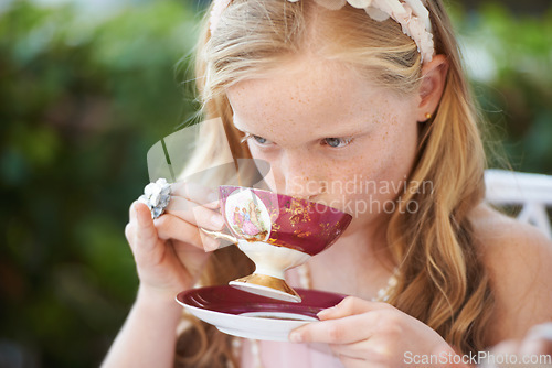 Image of Girl, kid and drinking tea in garden with party for birthday, celebration and playing outdoor in home. Person, child and porcelain cup in backyard of house with dress up, beverage and role play fun