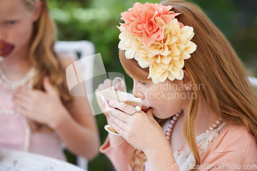 Image of Girl, child and drinking tea in garden with party for birthday, celebration and playing outdoor in home. Person, kid and porcelain cup in backyard of house with dress up, flower and role play fun