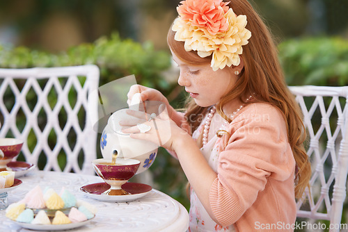 Image of Girl, child and pouring tea in garden with party for birthday, celebration and playing outdoor in home. Person, kid and porcelain cup in backyard of house with dress up, beverage and role play fun