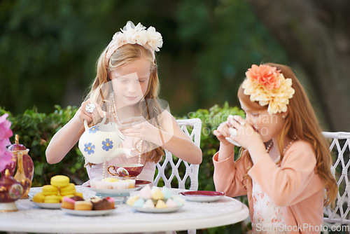 Image of Girls, children and tea party or outdoor fun for fantasy play in garden for cake snack, birthday or game. Kids, sisters and fancy dress up in nature or summer bonding in backyard, beverage or dessert