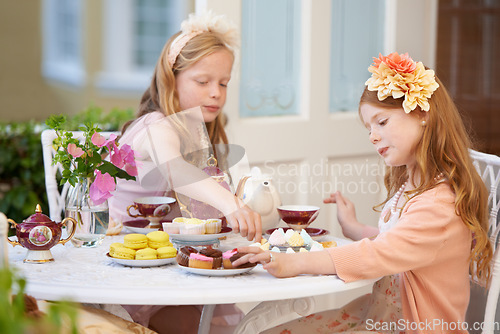 Image of Children, friends and tea in garden for party at birthday for snack for dress up game, fantasy or play. Female people, siblings and pot for hot drink in backyard for summer dessert, lunch or macarons