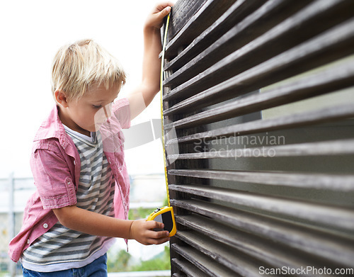 Image of Cute, measuring tape and boy kid doing maintenance on wood gate for fun or learning. Focus, equipment and young child working on repairs with tool for home improvement outdoor at modern house.