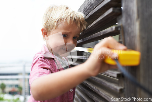 Image of Happy, measuring tape and young child doing maintenance on wood gate for fun or learning. Smile, equipment and cute boy kid working on repairs with tool for home improvement outdoor at house.
