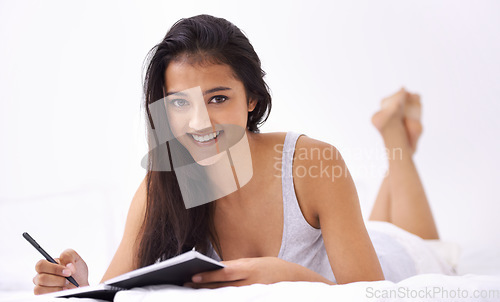 Image of Woman, bed and writing portrait in the morning with diary and book in a home with a smile. Indian female person, bedroom and wake up on duvet with peace and calm in a house on a blanket with comfort