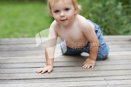 Image of Baby, portrait on floor outdoor for development with relax, curiosity and early childhood in backyard of home. Toddler, child and crawling on ground for wellness, milestone and exploring with playing