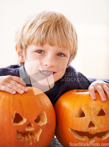 Image of Boy, portrait and happy with pumpkin for halloween, celebration or decoration in kitchen of apartment or home. Kid, face and smile with vegetable for preparation, holiday or creative event in house