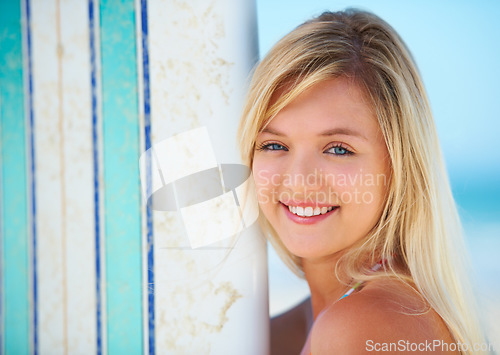 Image of Surfer, portrait and woman with a smile at beach in summer, vacation or holiday with sports, board or fun. Happy, face and person outdoor in sunshine with blue sky with ocean, travel and sea