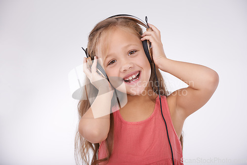 Image of Child, music and portrait of girl with headphones in studio for audio, subscription and streaming multimedia on white background. Excited kid listening to podcast, hearing sound and radio connection