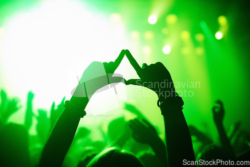 Image of Triangle hands, neon and person in concert audience for music, festival or performance on stage. Party, psychedelic and green light with crowd of people outdoor for event, disco or club celebration