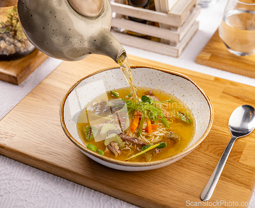 Image of Waiter pours broth into a chicken soup