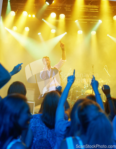 Image of Man, singing and band or crowd at live concert performance for rock party, music festival or audience. Male people, instruments and hand up or entertainment artist show or listening, weekend or event