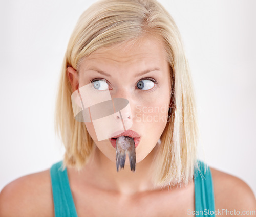 Image of Face, woman and eating tail of fish with surprise and shock on white background of studio. Crazy, diet and person with taste of weird seafood, cuisine and confused with gross or strange food in mouth