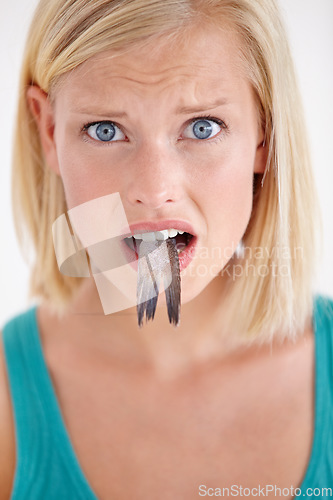 Image of Confused, woman and portrait eating fish, tail and surprise on white background of studio. Crazy, diet and person with doubt in weird seafood, cuisine and taste gross or strange food in mouth