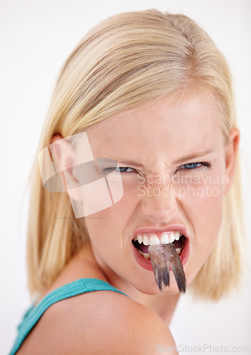Image of Woman, eating and portrait with fish, tail or dislike strange food in mouth on white background of studio. Crazy, diet and person with weird seafood, cuisine and disgust for taste of tuna or salmon