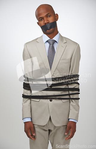 Image of Portrait, business and black man tied with rope, mouth covered with tape and compliance issue on white studio background. African person, employee or entrepreneur with control, policy or crisis