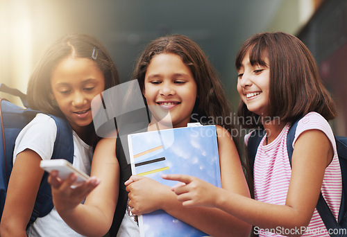 Image of Elementary school, group of friends or girls with phone, reading social media notification or download digital app. Diversity, students or happy kids pointing to mobile, tech or typing online for fun
