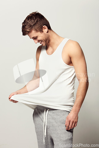 Image of Smile, morning and pajamas with a young man in studio on a white background to wake up in a good mood. Relax, happy and casual with a person looking at his vest or tank top for weekend chilling