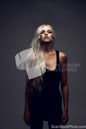 Image of Portrait, woman and confident in studio with fashion, style and trendy aesthetic with positive by gray background. Model, pride and cosmetic on face with wellness, make up and blonde in black dress