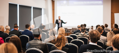 Image of Speaker giving a talk in conference hall at business event. Rear view of unrecognizable people in audience at the conference hall. Business and entrepreneurship concept.